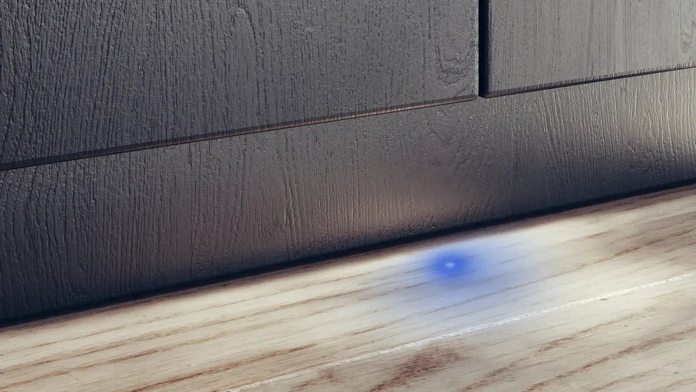 Close-up of a textured dark gray surface meeting a wooden floor.