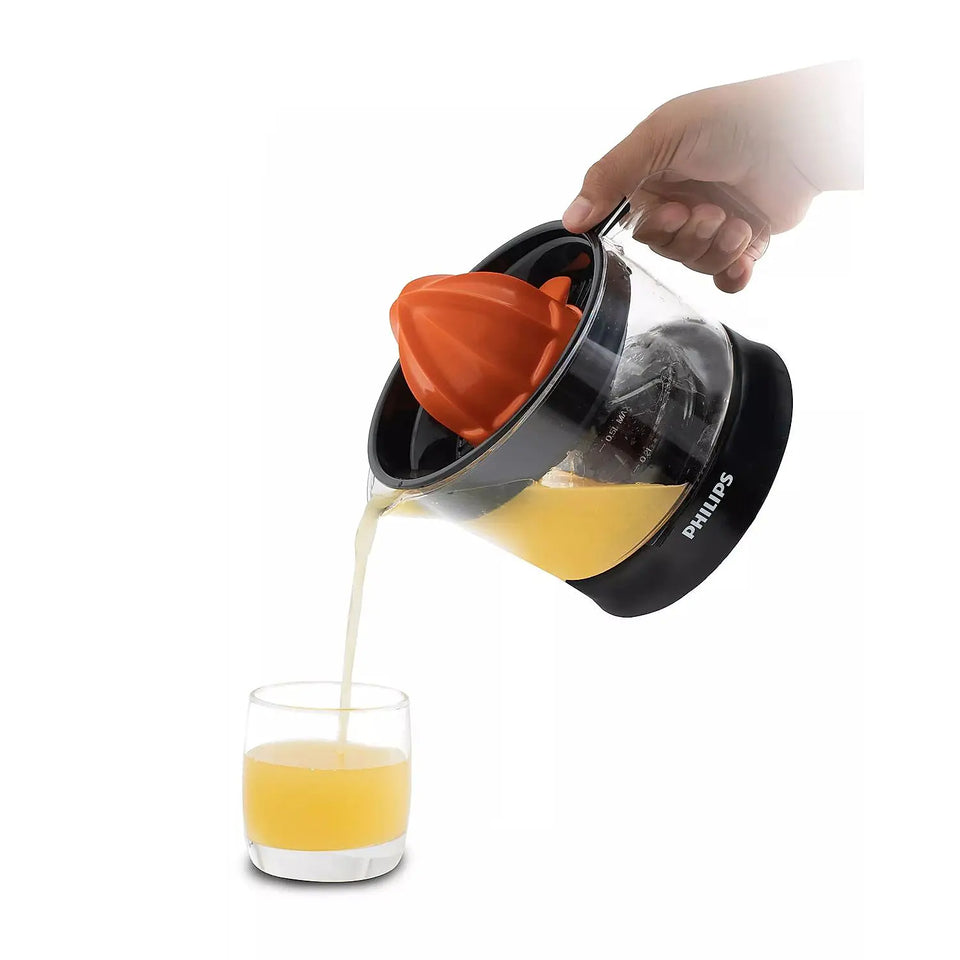 Philips HR2777/00 citrus press jar being tilted to pour fresh orange juice into a glass