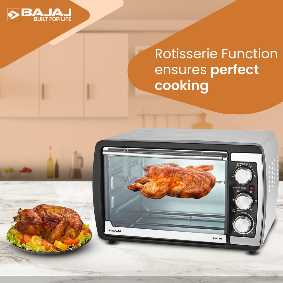 Bajaj 2000 TM oven roasting a chicken on the rotisserie, with a plated roast chicken beside it