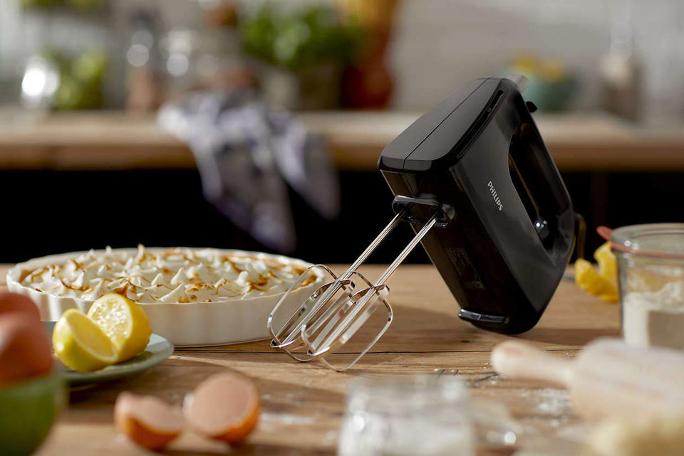 Philips HR3705/10 hand mixer on a kitchen worktop with a meringue pie, lemons, eggs and flour