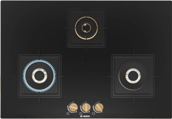 Top view of Bosch PND7B6F20I 75 cm gas hob showing three brass burners, heat shields and brass-finish front knobs
