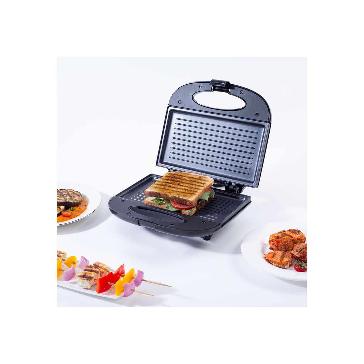 Wonderchef Prato Plus 63154445 sandwich griller open with a grilled sandwich on the plate, surrounded by grilled aubergine, chicken and paneer skewers