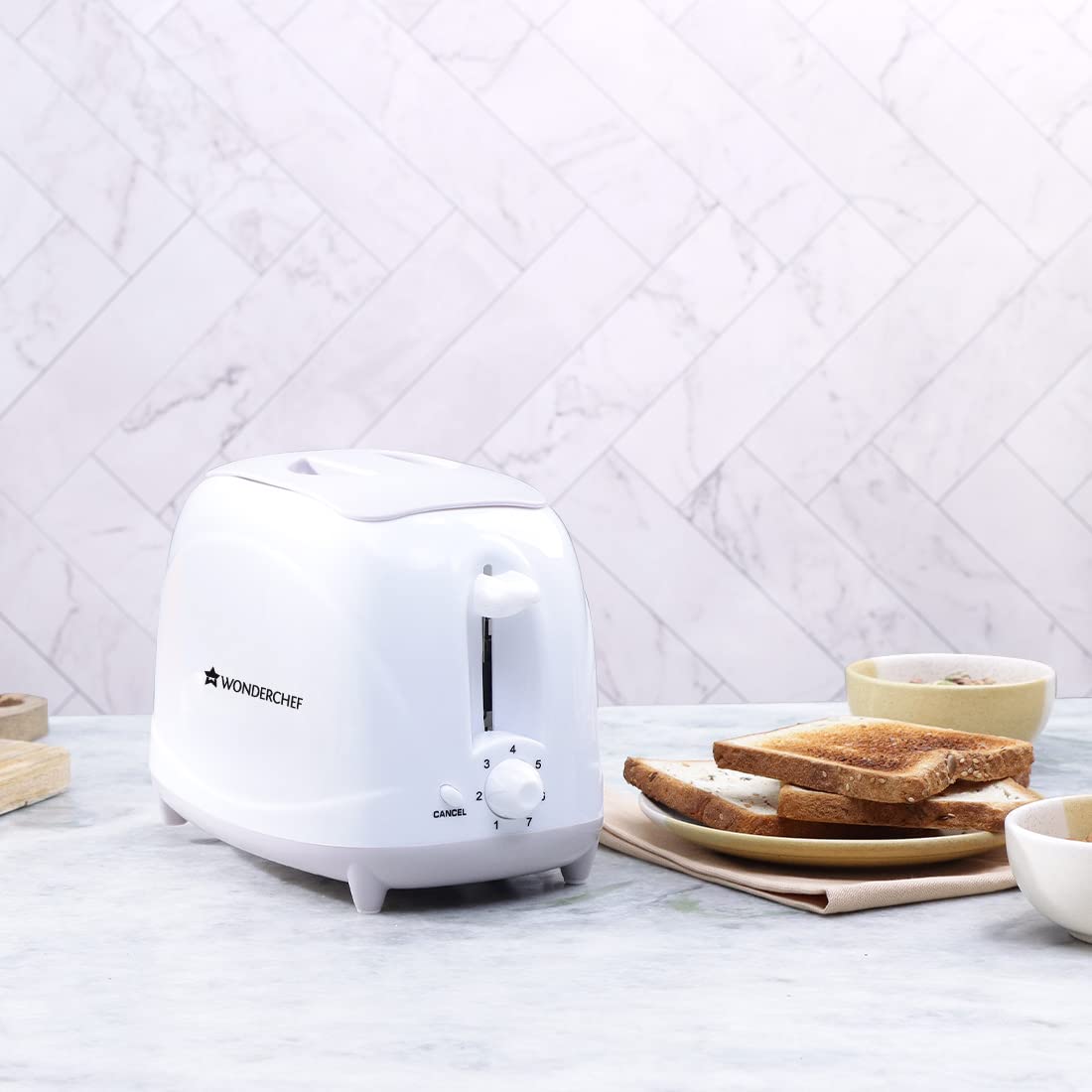 Wonderchef Ultima white toaster on a marble counter next to a plate of toasted bread