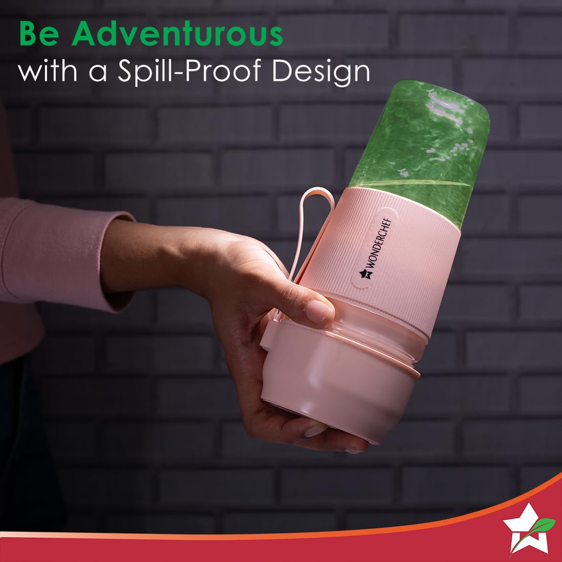 Hand holding the Wonderchef Nutri Cup 63154460 pink portable blender with a green blended drink and screw-top base