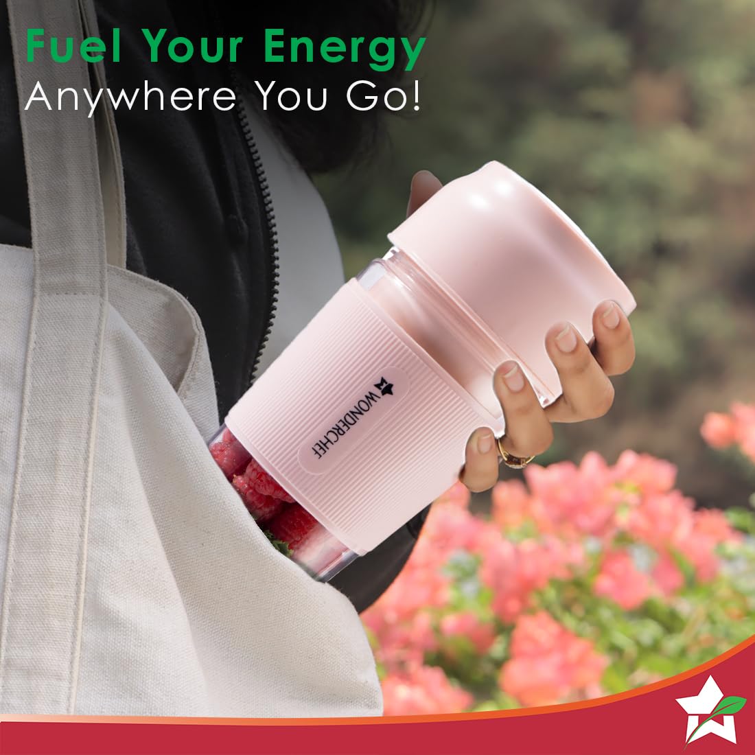Hand holding the Wonderchef Nutri Cup 63154460 pink portable blender filled with raspberries, carried near a tote bag
