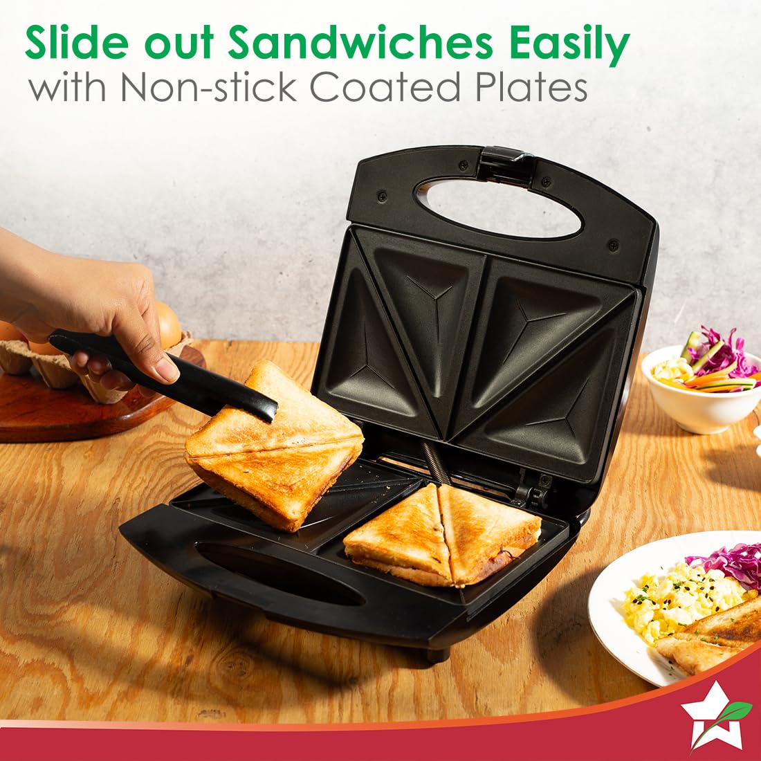 Wonderchef Acura Plus sandwich maker with a toasted sandwich being lifted out with tongs from the non-stick plates