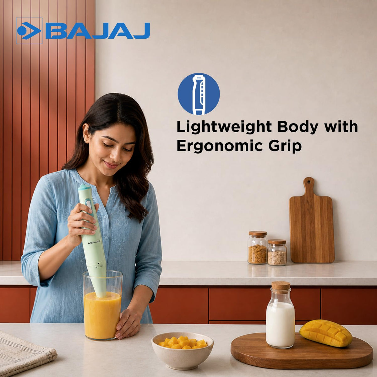 Woman blending a mango drink in a tall glass with the lightweight Bajaj HB 20 hand blender