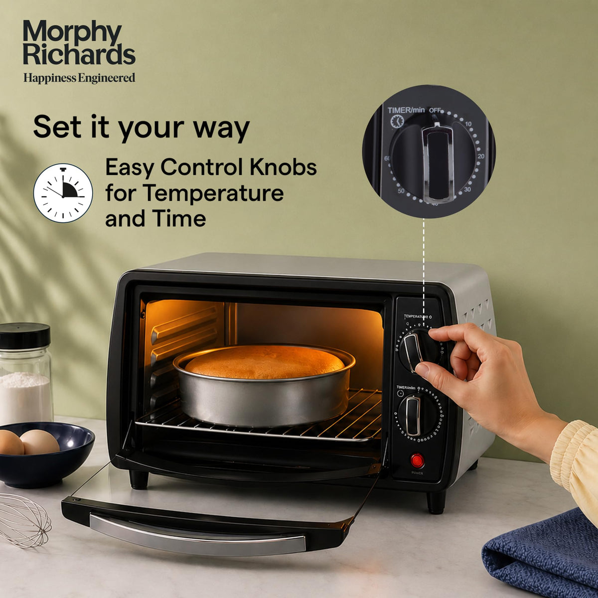 Hand turning the temperature knob on the Morphy Richards 510065 10 L OTG oven, with a close-up of the timer dial