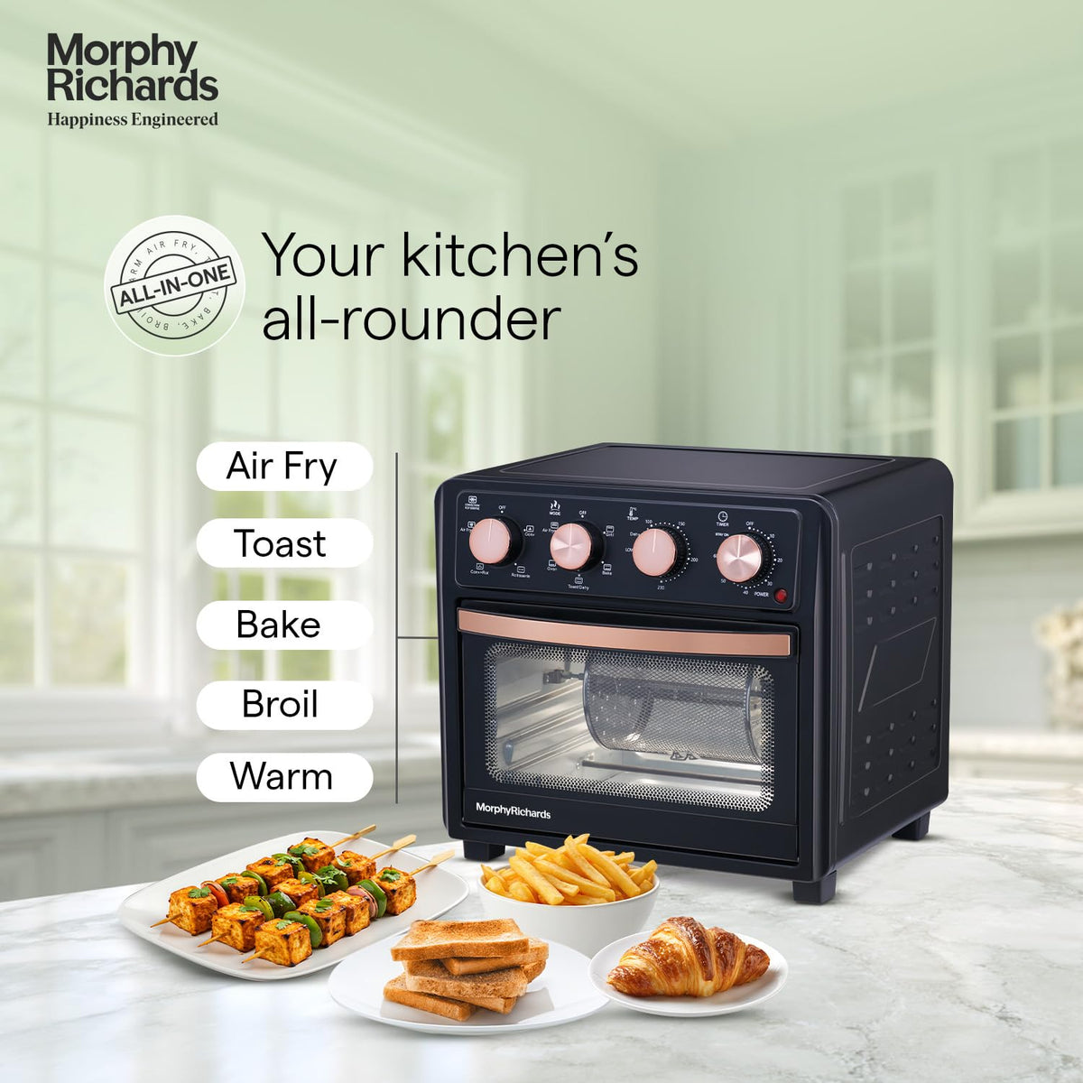 Morphy Richards 510060 AirCrisp air fryer oven with Air Fry, Toast, Bake, Broil and Warm labels and plates of paneer tikka, fries, toast and a croissant