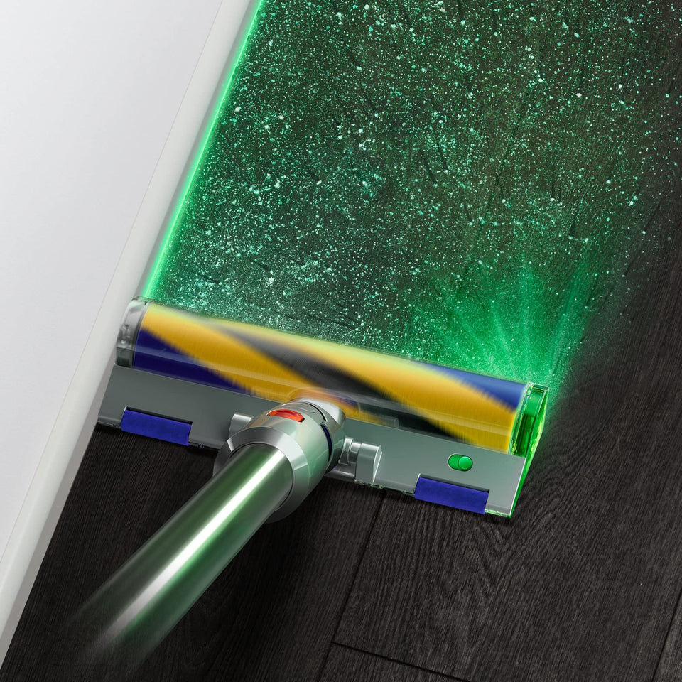 Close-up of the Dyson V15 Detect 381356-01 illuminated cleaner head showing fine dust on a dark floor along a skirting board