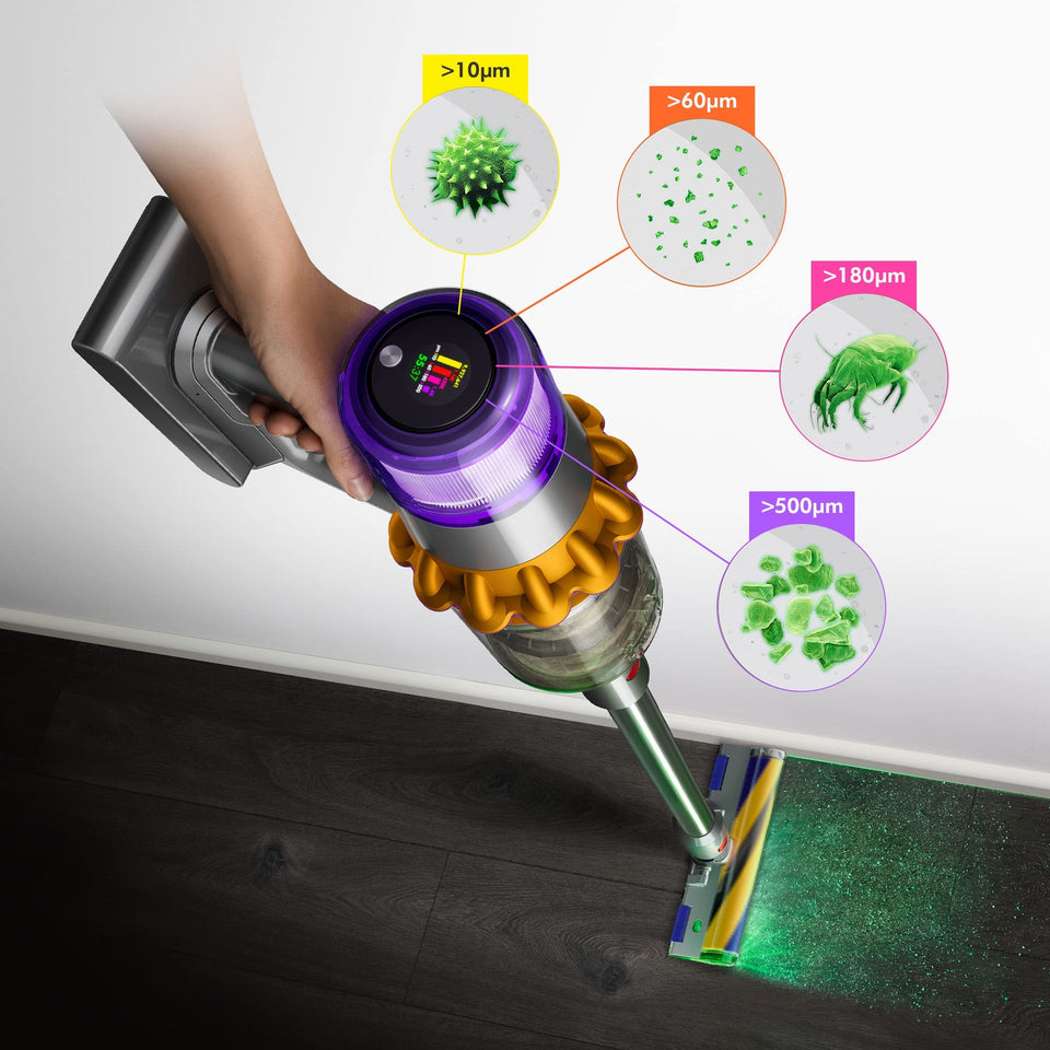 Dyson V15 Detect 381356-01 held in hand showing the LCD screen and dust particle size callouts while the cleaner head lights up a dark wood floor