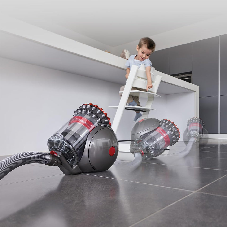 Dyson Big Ball 492954-01 vacuum moving across a tiled kitchen floor while a child watches from a high chair