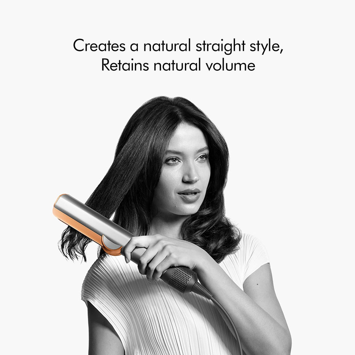 Woman styling her hair with the Dyson Airstrait 408213-01, with the text creates a natural straight style, retains natural volume
