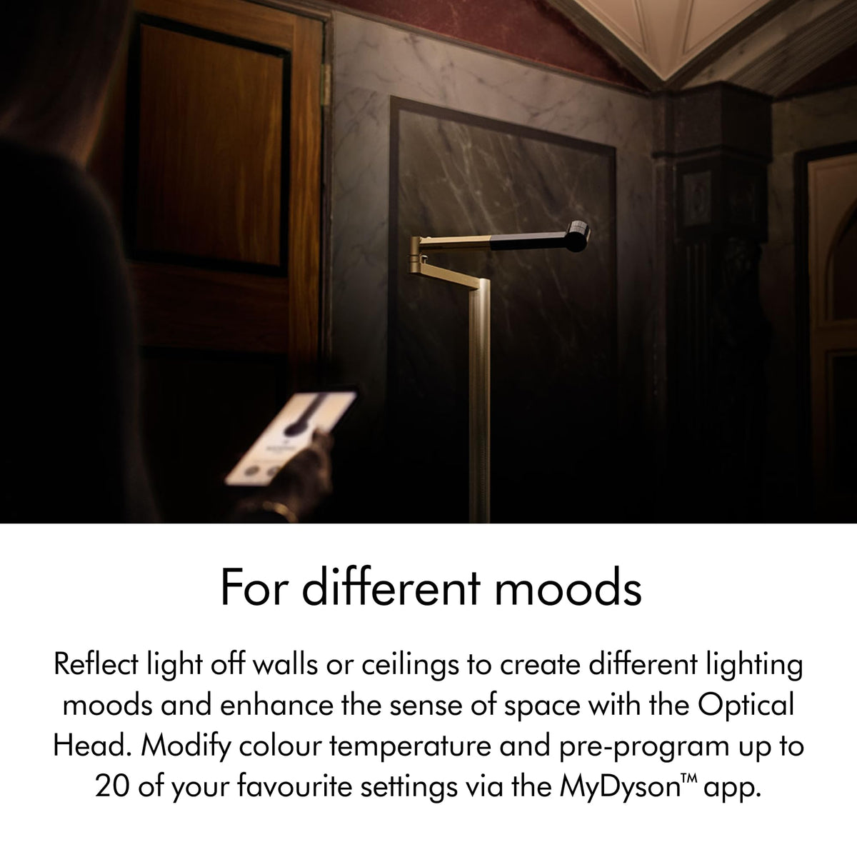 Dyson Solarcycle Morph CF06 floor light reflecting light off a wall, with a phone showing the MyDyson app