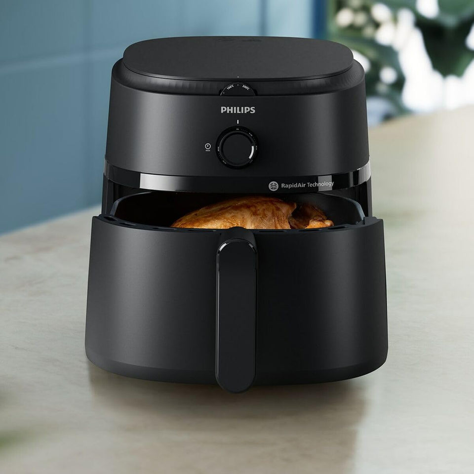 Philips NA130/00 air fryer on a kitchen counter with the basket partly open showing a roast chicken
