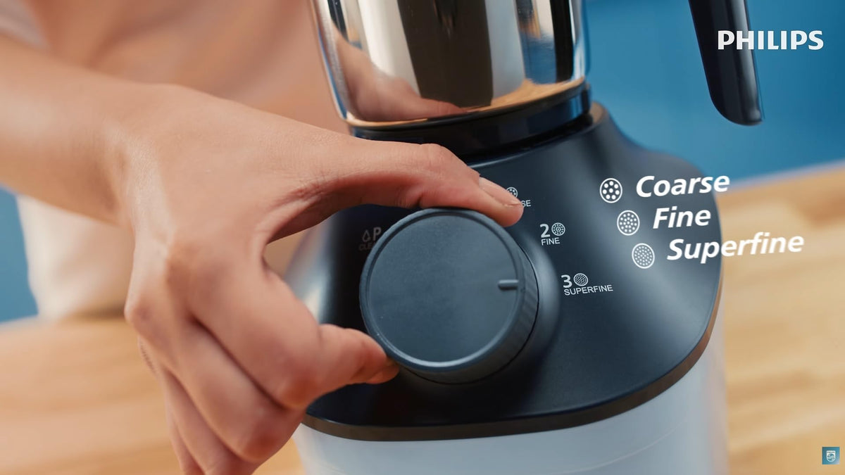 Hand turning the control dial of the Philips HL7773/01 mixer grinder, with Coarse, Fine and Superfine texture labels