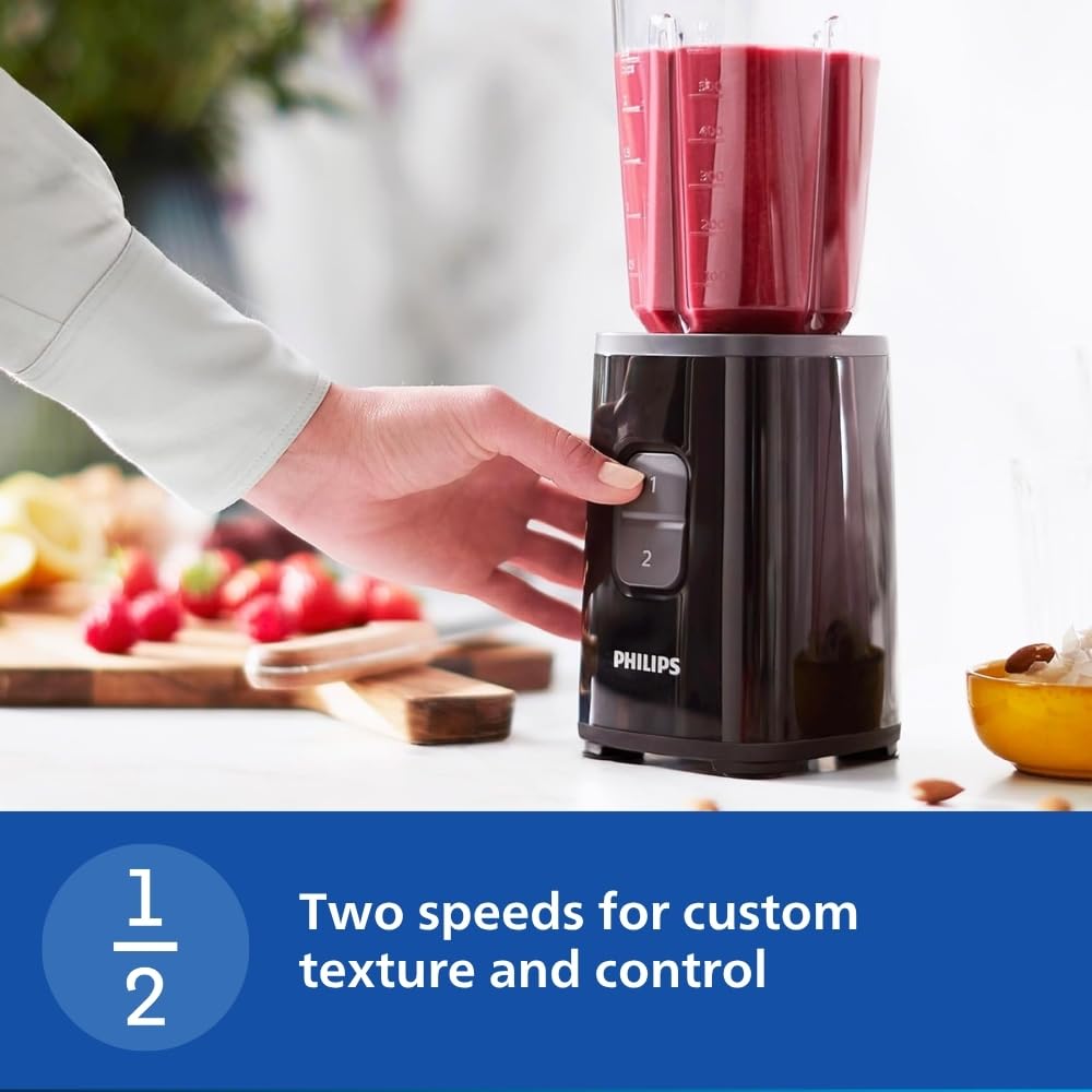 Hand pressing speed button 1 on the Philips HR2602/90 blender with a jar of red smoothie